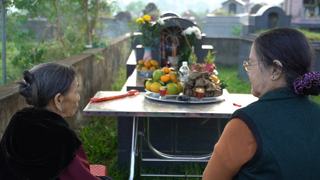 Hai người mẹ ngồi trước mộ con trước giờ khai quật (ảnh: VTV)