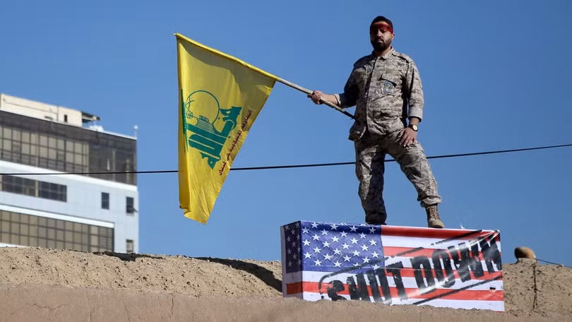 Một lính thuộc lực lượng đặc biệt Quds phất cờ Thánh chiến dẫm trên quốc kỳ Mỹ (Ảnh: Reuters)