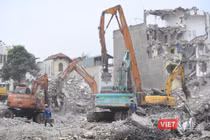 Tại hiện trường, các máy xúc hoạt động liên tục, sử dụng càng thép để phá dỡ các mảng bê tông, thu gom sắt thép và phế liệu xây dựng, sau đó vận chuyển ra khỏi khu vực để trả lại mặt bằng sạch.