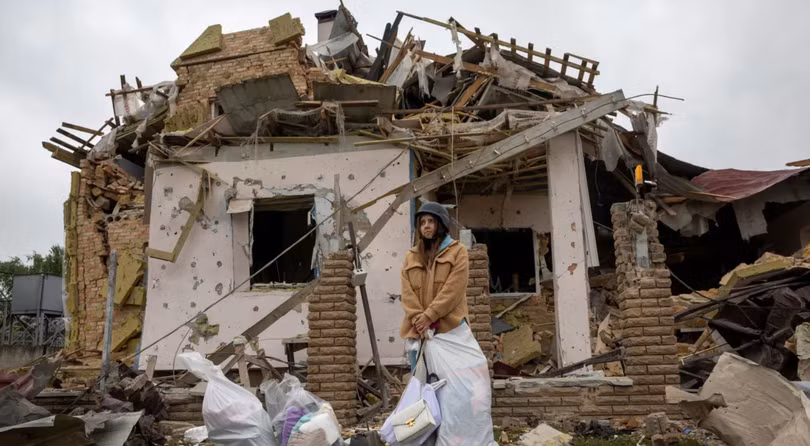 Một người phụ nữ đứng cùng đồ đạc của mình bên ngoài ngôi nhà của cô ở Markhalivka, thuộc khu vực Kiev của Ukraine, nơi đã bị phá hủy trong cuộc không kích của Nga vào hôm 25/5. Ảnh: Reuters.