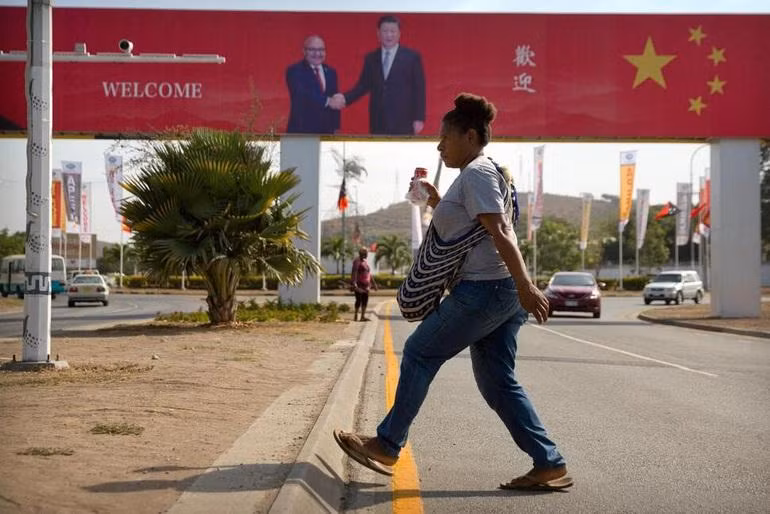 Một phụ nữ bước qua con đường, nơi có áp phích chào đón chuyến thăm của Chủ tịch Trung Quốc Tập Cận Bình ở Papua New Guinea năm 2018 (Ảnh: AP).