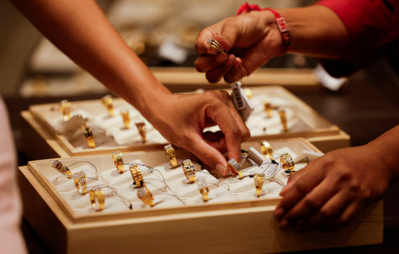 Một nhân viên bán hàng giới thiệu nhẫn vàng cho khách mua tại một phòng trưng bày trang sức ở Ahmedabad, Ấn Độ, ngày 8/10. Ảnh: Reuters.