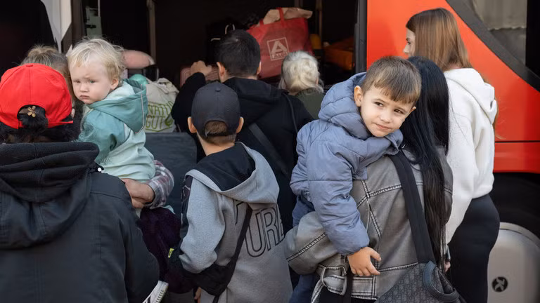 Người tị nạn từ Ukraine đứng cạnh một chiếc xe buýt tại trung tâm tiếp nhận người tị nạn đầu tiên ở Hesse, Đức. Ảnh: Getty.