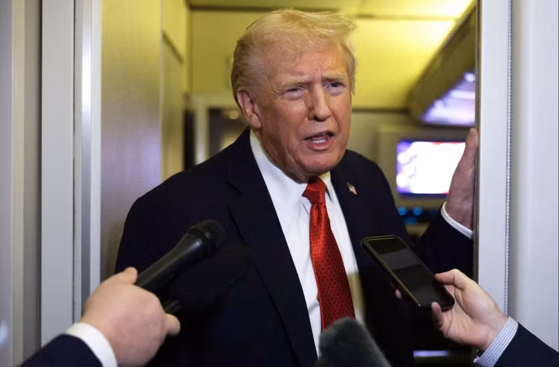 Tổng thống Mỹ Donald Trump phát biểu với các phóng viên trên chuyên cơ Không lực Một. Các nhà phân tích cho rằng quyết định mở rộng danh sách đen thương mại của Mỹ vào cuối tháng 9 có thể đã châm ngòi căng thẳng trong cuộc chiến thương mại Mỹ-Trung. Ảnh: AFP.