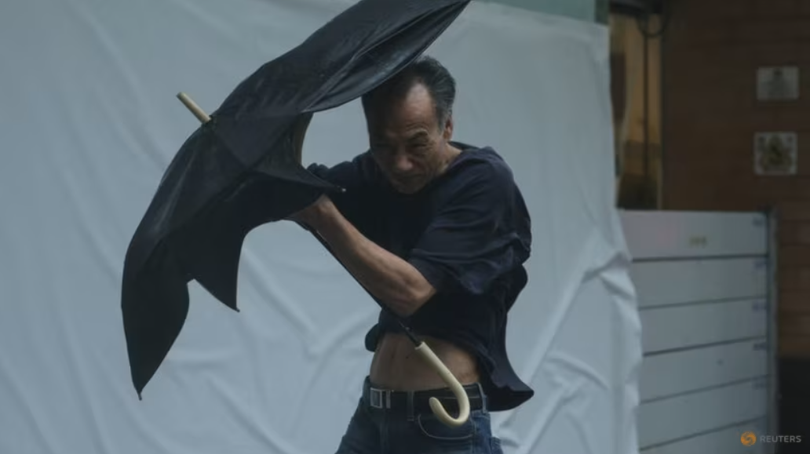 Một người đàn ông vật lộn với chiếc ô khi đi bộ ngược gió mạnh khi cơn bão Wipha tiến gần đến Hong Kong, Trung Quốc vào ngày 20/7. Ảnh: Reuters.