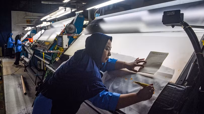 Một công nhân kiểm tra vải xuất khẩu trước khi nhuộm tại nhà máy Trisula Textile Industries ở Cimahi, Tây Java vào ngày 15/4. Ảnh: AFP.