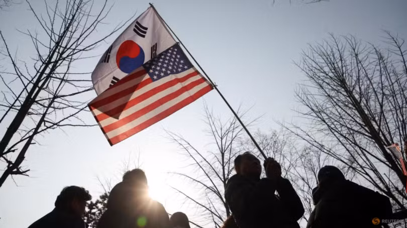 Một người cầm cờ Hàn Quốc và cờ Mỹ ở Uiwang, Hàn Quốc vào ngày 8/3. Ảnh: Reuters.