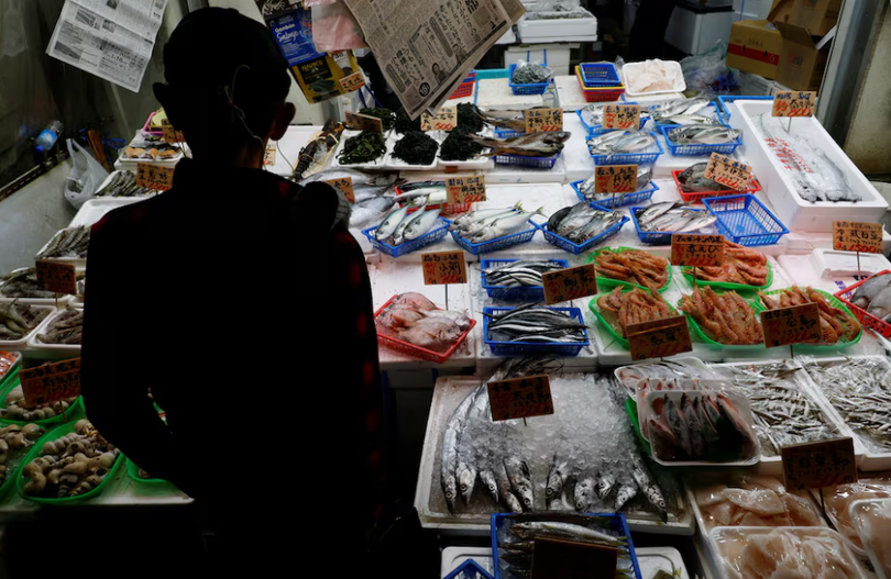 Một khách hàng đang xem hải sản tại một cửa hàng ở Tokyo, Nhật Bản ngày 19/11. Ảnh: Reuters.