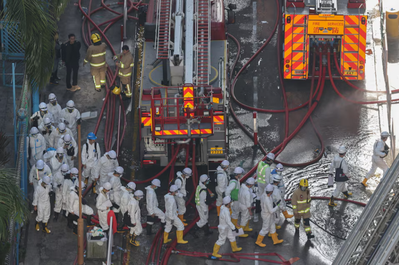 Cảnh sát mặc đồ bảo hộ đi bộ gần hiện trường vụ cháy chung cư tại khu nhà ở Wang Fuk Court sau vụ hỏa hoạn chết người ở Tai Po, Hong Kong, Trung Quốc, ngày 29/11. Ảnh: Reuters.