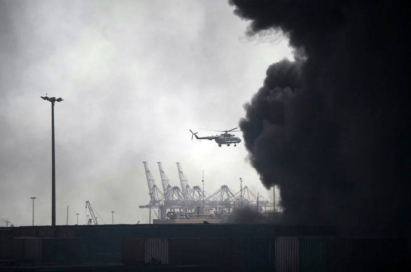 Một chiếc trực thăng bay qua làn khói đen bao trùm hiện trường vụ nổ tại cảng ở Iran, khiến ít nhất năm người thiệt mạng và hơn 700 người khác bị thương. Ảnh: AFP.
