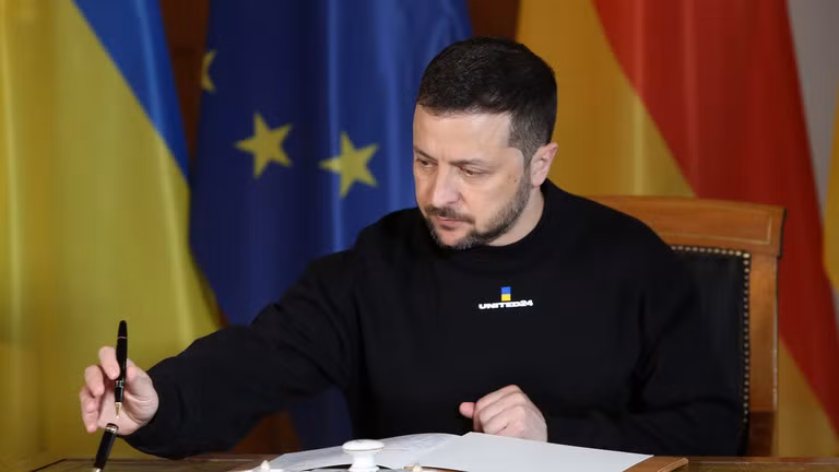 Tổng thống Ukraine Volodymyr Zelensky đang ký vào một cuốn sổ lưu bút. Ảnh: Getty.