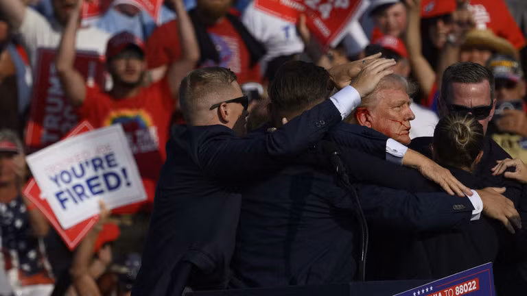 Donald Trump được nhân viên Mật vụ dẫn đi sau khi có tiếng súng vang lên tại cuộc vận động tranh cử ở Butler, Pennsylvania (Ảnh: AFP)