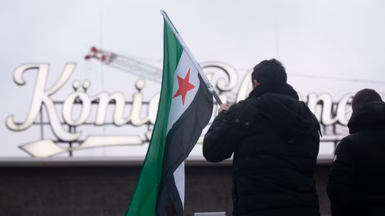 Người Syria tị nạn phản ứng trước những diễn biến mới ở Syria tại Ga trung tâm Duisburg ở Duisburg, Đức. Ảnh: Getty.