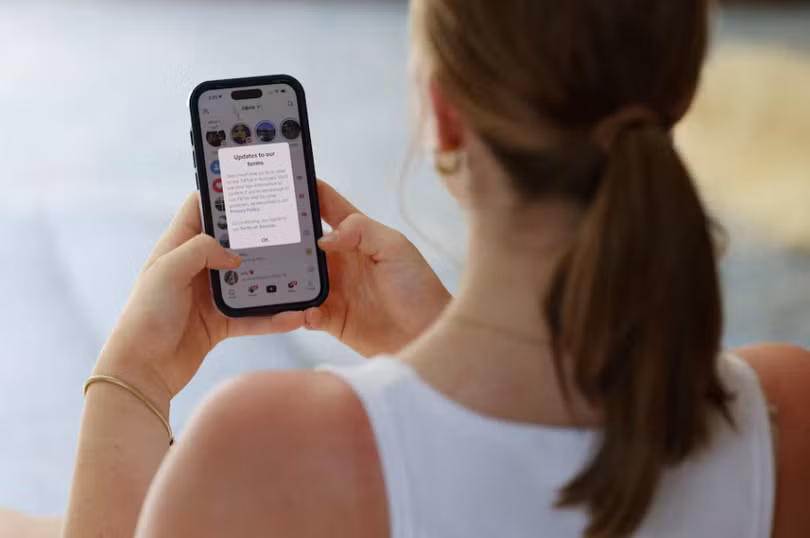 Một thiếu niên với chiếc điện thoại di động hiển thị tin nhắn từ TikTok, trong bối cảnh luật cấm sử dụng mạng xã hội đối với người dùng dưới 16 tuổi ở Australia có hiệu lực, ngày 10/12. Ảnh: Reuters.