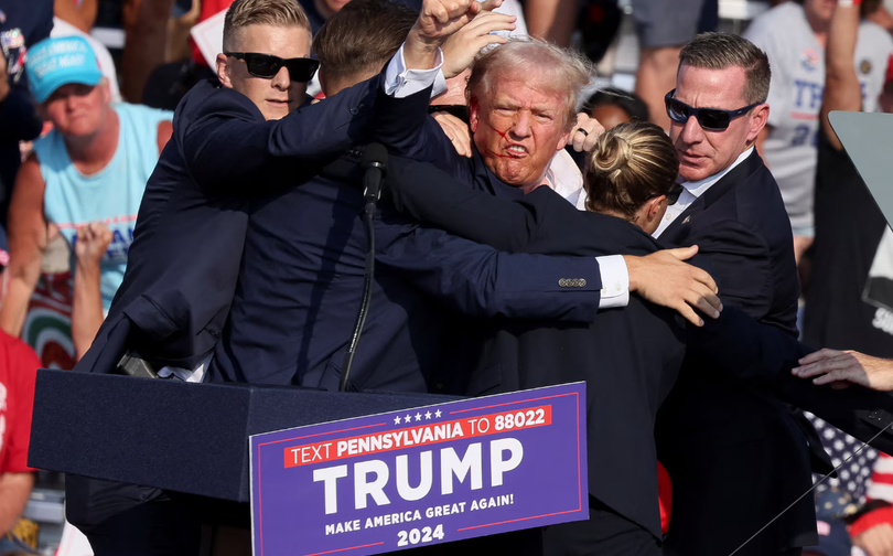 Ông Donald Trump ra hiệu với khuôn mặt đầy máu sau khi bị bắn vào tai phải trong một cuộc vận động tranh cử ở Butler, Pennsylvania, Mỹ ngày 13/7/2024. Ảnh: Reuters.