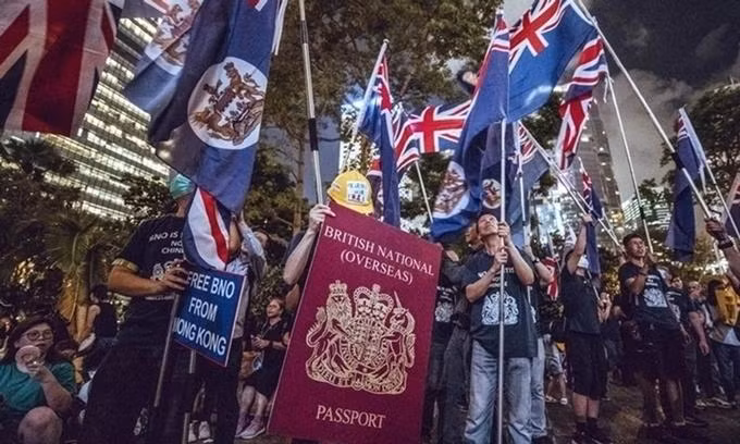 Người biểu tình Hong Kong cầm hình ảnh mô phỏng hộ chiếu hải ngoại Anh cuối tháng 6 (Ảnh: SCMP)