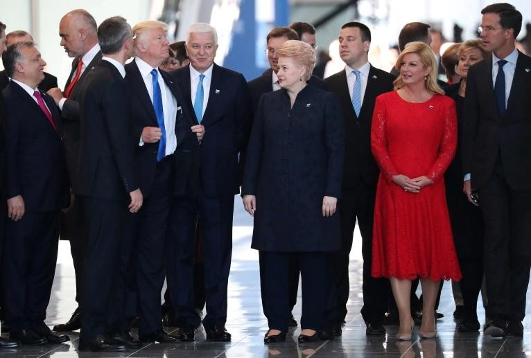 Ông Trump chỉnh lại áo khoác sau khi xô Thủ tướng Montenegro sang một bên (Ảnh: Reuters)