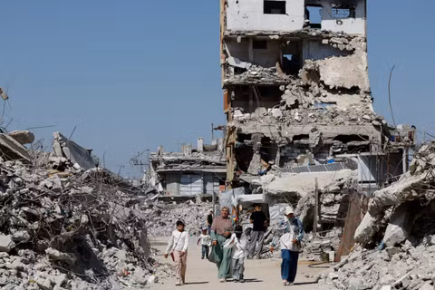 Người dân Palestine đi bộ ngang qua đống đổ nát của các tòa nhà dân cư bị phá hủy trong chiến tranh, tại trại tị nạn Jabalia ở phía bắc Dải Gaza, ngày 5/8. Ảnh: Reuters.