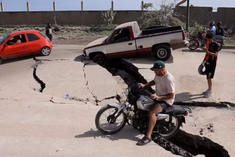 Một người đàn ông ngồi trên xe đạp trên con đường bị hư hỏng ở La Guaira, Venezuela, ngày 25/6. Ảnh: Reuters.