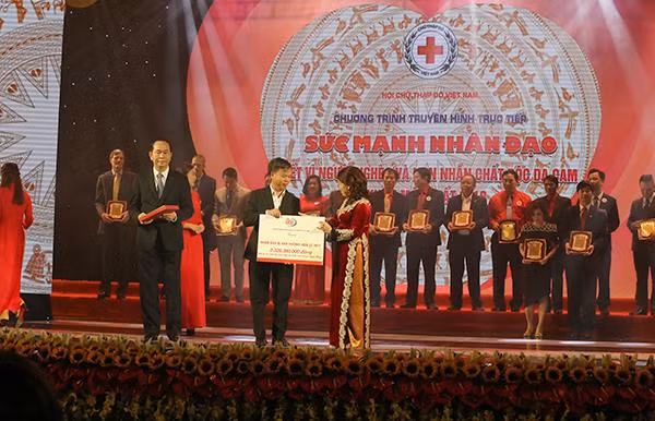 Phó tổng giám đốc Tổng công ty VTC Dương Thế Lương đại diện Cổng 1400 trao biển biểu trưng hơn 2,3 tỉ đồng cho bà Nguyễn Thị Xuân Thu-Chủ tịch Hội Chữ thập đỏ Việt Nam tối 7/1/2018, tại Hà Nội.
