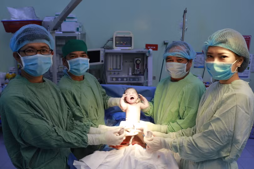 BS. Nguyễn Hữu Dự - Giám đốc BV Phụ sản TP. Cần Thơ (trong cùng bên phải) cùng ê kíp bác sĩ vui mừng chào đón bé trai chào đời trong thời khắc giao thừa. Cùng lúc đó, bé trai giơ hai tay như thay cho lời chúc mừng năm mới khiến ai nấy đều bật cười. Ảnh: BVCC