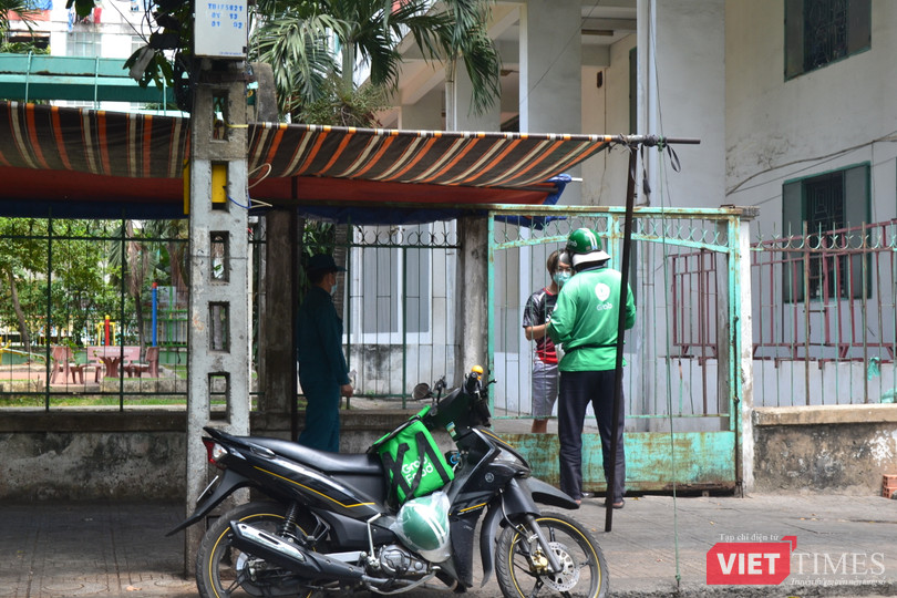 Một người dân trong chung cư đặt cơm trưa, có lực lượng an ninh theo sát. Ảnh: Nguyễn Trăm