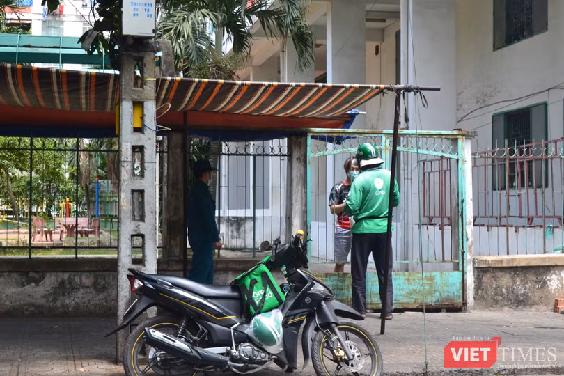 Một người dân trong chung cư đặt cơm trưa, có lực lượng an ninh theo sát. Ảnh: Nguyễn Trăm