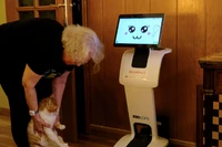 Irene Veglison, 67 tuổi, ôm con mèo tên Sweet của mình bên cạnh con robot có biệt danh "Sandi". Ảnh: 