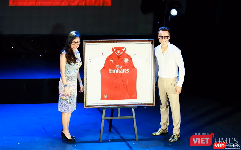 Người tặng áo (bên trái ảnh) và ca sĩ Hoàng Bách lên nhận thay vợ đã đấu giá thành công chiếc áo có chữ ký của các cầu thủ đội tuyển Arsenal - 1000$