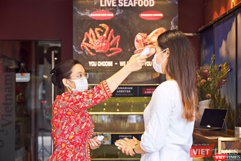 Đo thân nhiệt cho khách vào nhà hàng, kiểm tra khai báo y tế, thẻ xanh COVID-19. Ảnh: HB