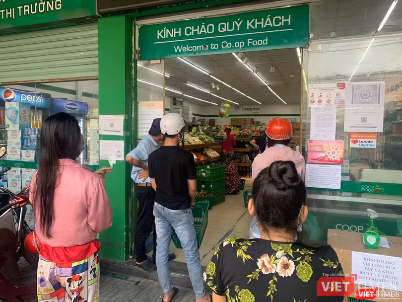 Xếp hàng giãn cách đợi đến lượt vào siêu thị Co.op Food mua thực phẩm - Ảnh: Hoà Bình