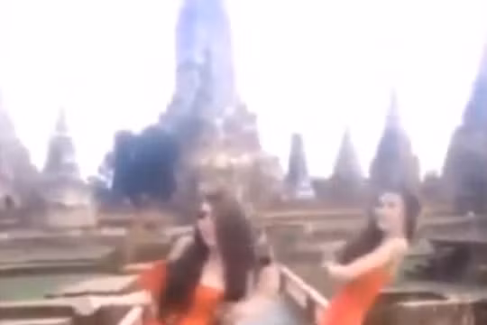 Hai phụ nữ mặc váy cam ngắn cũn nhảy nhót trước đền thiêng