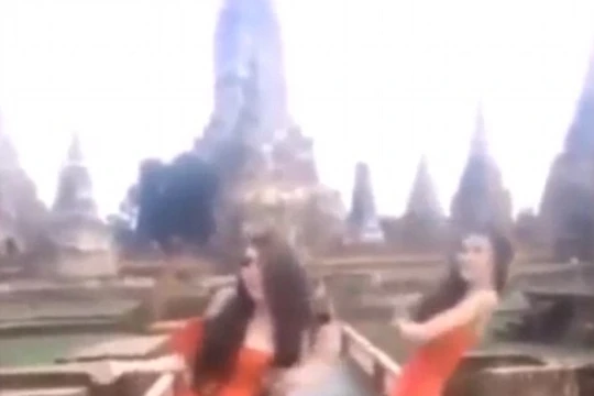 Hai phụ nữ mặc váy cam ngắn cũn nhảy nhót trước đền thiêng