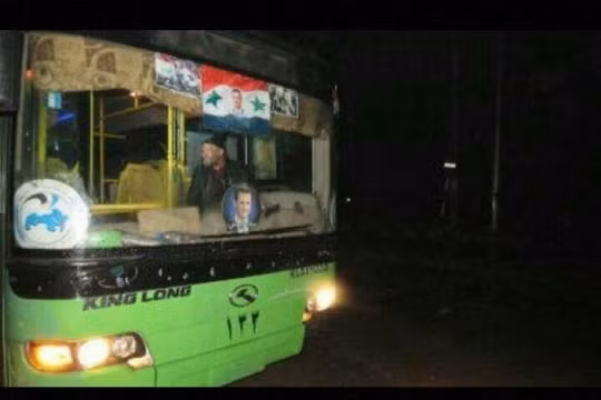 Xe buýt màu xanh của chính quyền Syria chở chiến binh thánh chiến lên đường về Idlib