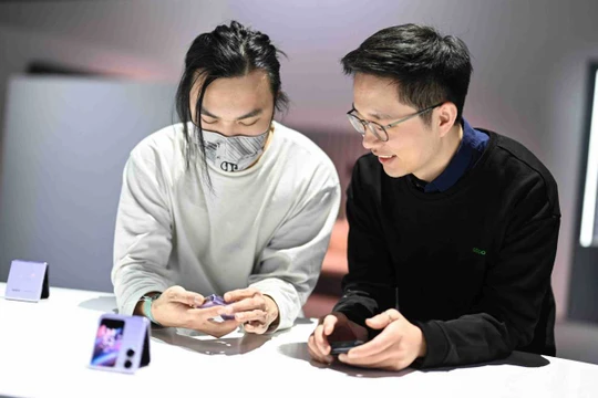 Người tiêu dùng kiểm tra điện thoại thông minh có thể gập lại của Oppo Find N2 Flip ở Thâm Quyến, tỉnh Quảng Đông tháng 12. Ảnh China Daily.