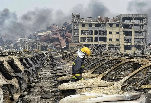Lính cứu hỏa đi giữa các phương tiện bị phá hủy trong vụ nổ hôm 12/8. Ảnh: Reuters
