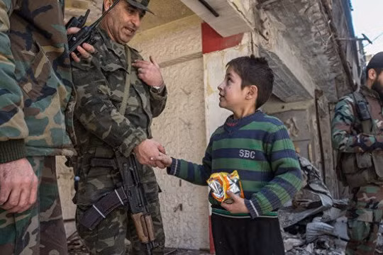 Một sĩ quan cao cấp quân đội Syria nói chuyện với em bé trong khu vực vừa giải phóng ở Aleppo