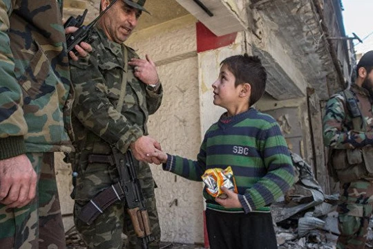 Một sĩ quan cao cấp quân đội Syria nói chuyện với em bé trong khu vực vừa giải phóng ở Aleppo