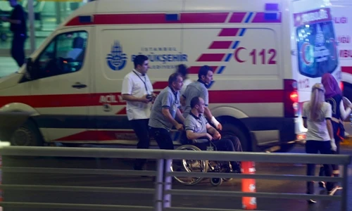 Nhân viên y tế hỗ trợ một người ngồi xe lăn rời khỏi sân bay Ataturk. Ảnh: Reuters.