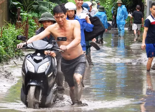 Người dân phải lội bùn, di dời một số vật dụng ra khỏi khu vực ngập. Ảnh: Giang Chinh.