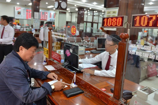 Khách hàng giao dịch tại một ngân hàng ở Q.1, TP.HCM - Ảnh: D.Ph. 