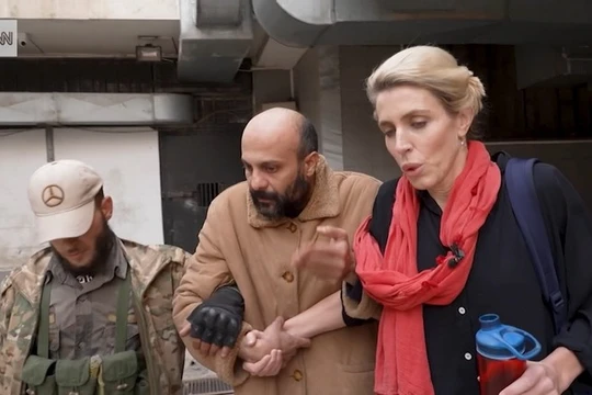 Hình ảnh tù nhân (giữa) được nhà báo Clarissa Ward (phải) của CNN và một người đàn ông có vũ trang hộ tống khỏi nhà giam ở Syria. Ảnh: CNN.