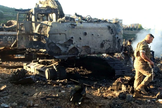 Binh sĩ Lebanon đi cạnh một máy đào bị phá hủy sau cuộc không kích của Israel. Ảnh: AFP.