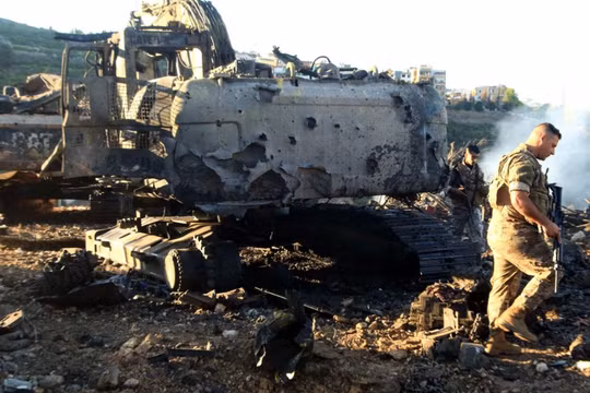 Binh sĩ Lebanon đi cạnh một máy đào bị phá hủy sau cuộc không kích của Israel. Ảnh: AFP.