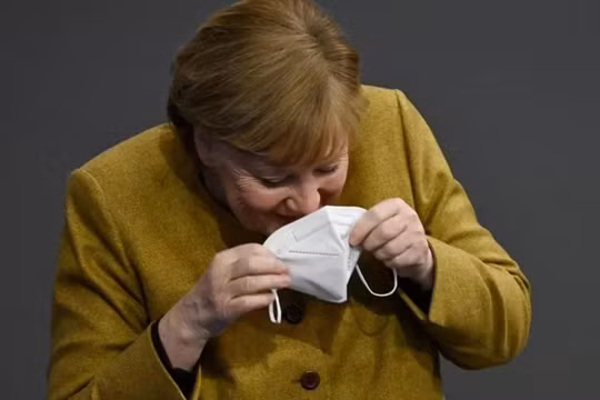 Bà Merkel nhịn cười khi đang đeo lại khẩu trang của mình (Ảnh: Getty)