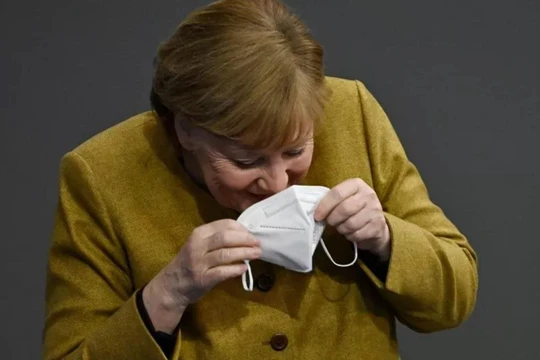 Bà Merkel nhịn cười khi đang đeo lại khẩu trang của mình (Ảnh: Getty)