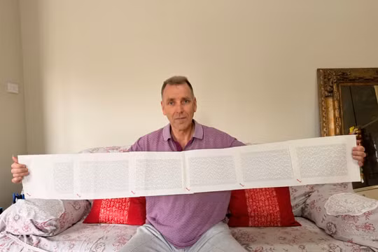 Laurence Watkins, một nhân viên bảo vệ đã nghỉ hưu đến từ Auckland, New Zealand, cầm trên tay giấy khai sinh dài 6 trang, trong đó ghi đầy đủ 2.253 cái tên của ông. Ảnh: CNN.