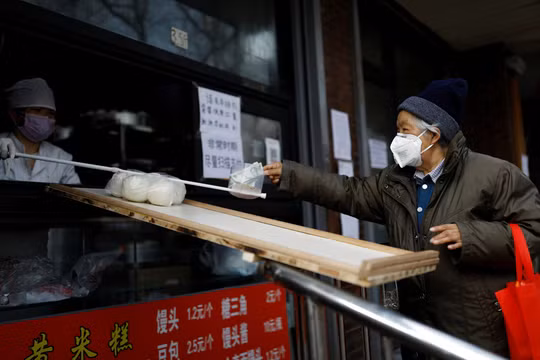 Lo sợ virus corona, người bán hàng ở Bắc Kinh không dám trực tiếp nhận tiền của khách mua (Ảnh: Reuters)