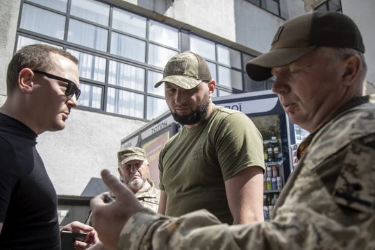 Các sĩ quan tuyển dụng kiểm tra giấy tờ của khi họ tìm kiếm những người đàn ông trong độ tuổi chiến đấu ở Kharkov, Ukraine. Ảnh: Getty.