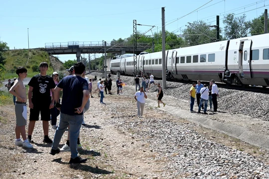 Hành khách đứng cạnh một chuyến tàu dừng lại gần Cordoba, Tây Ban Nha. Ảnh: AFP